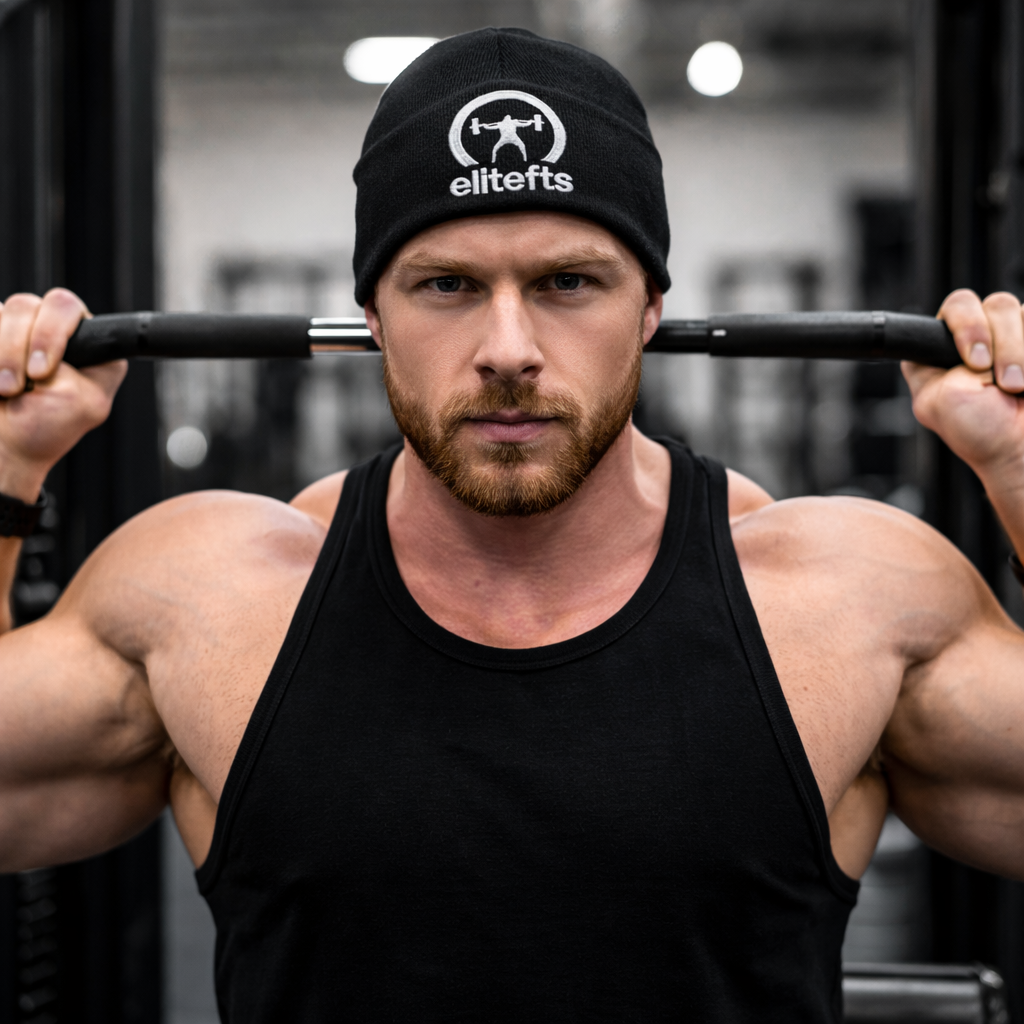 Muscular man lifting a barbell with an 'elitefts' beanie in a gym setting