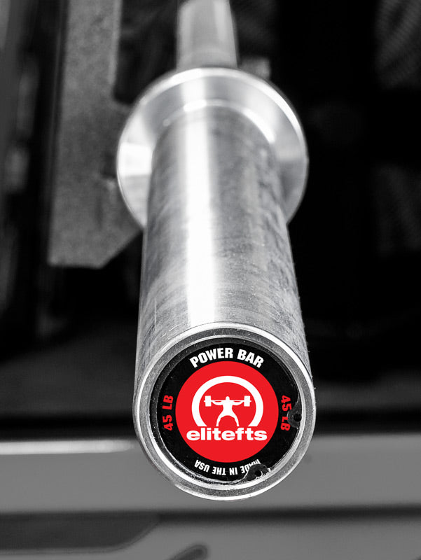 Silver power bar with Elitefts logo on a blurred gym background